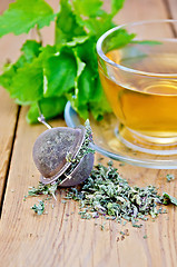 Image showing Herbal tea from melissa in cup with strainer on board