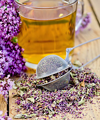 Image showing Herbal tea from oregano with strainer in glass mug