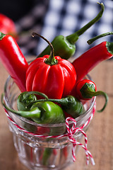 Image showing Red and green chili peppers in glass