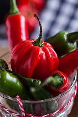 Image showing Red and green chili peppers in glass