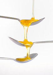 Image showing Honey dripping over three silver teaspoonful 