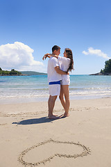 Image showing happy couple have fun on the beach with heart on sand