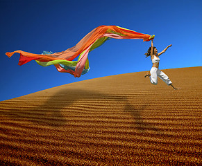 Image showing Rainbow woman jumping over the dunes