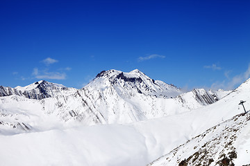 Image showing Off-piste slope and snowy mounts against blue sky