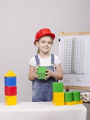 Image showing The girl in helmet builds a house on drawing