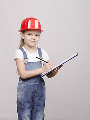 Image showing engineer child stands helmet and writes in folder