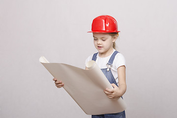 Image showing The girl in helmet looks drawing