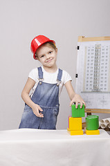 Image showing Girl Builder in helmet builds a house on drawing