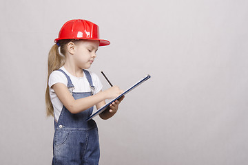 Image showing child stands helmet and writes in the folder