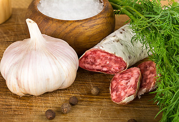 Image showing sliced salame on cutting board, with dill, pepper, salt