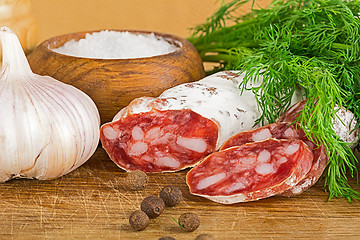 Image showing sliced salame on cutting board, with dill, pepper, salt