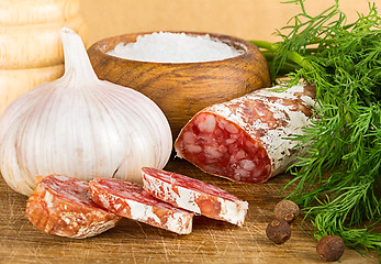 Image showing sliced salame on cutting board, with dill, pepper, salt