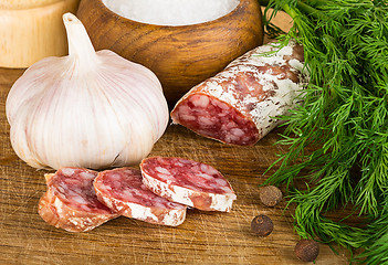 Image showing sliced salame on cutting board, with dill, pepper, salt