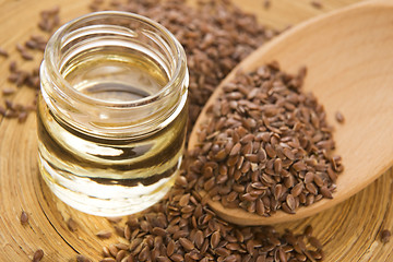 Image showing Linseed oil and flax seeds on wooden background 