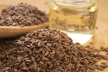 Image showing Linseed oil and flax seeds on wooden background 