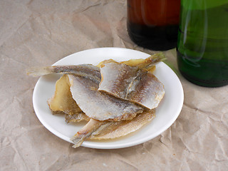 Image showing fish on white plate and beer bottle