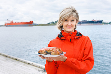 Image showing Happy woman holding cooked crab on plate