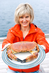 Image showing Happy woman giving cooked crab on plate