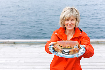 Image showing Happy woman giving cooked crab on plate