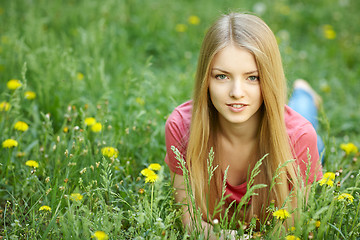 Image showing Spring girl lying on the field of dandelions