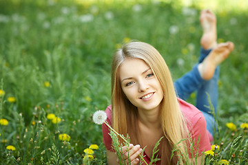 Image showing Spring girl lying on the field of dandelions