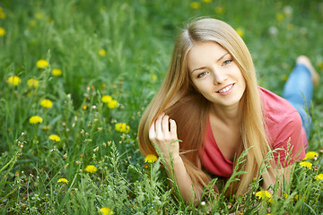 Image showing Spring girl lying on the field of dandelions