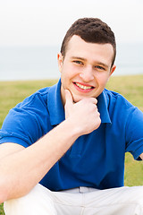 Image showing Happy young man sitting on lawn