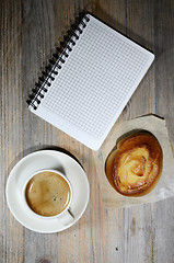 Image showing cup of espresso, checkered notebook and bun