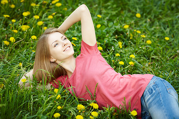 Image showing Spring girl lying on the field of dandelions