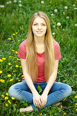 Image showing Female sitting on the field of dandelions