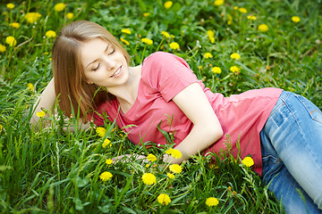 Image showing Spring girl lying on the field of dandelions