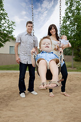 Image showing Father And Mother Pushing Boy On Swing