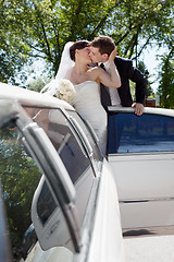 Image showing Newlywed Couple Standing Beside Limousine