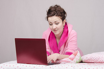 Image showing The surprised girl in bed works for laptop