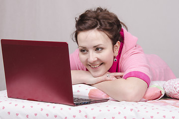 Image showing Cheerful girl in bed works for laptop