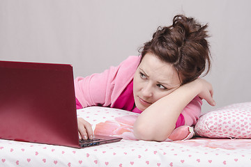 Image showing Girl in bed with alarm looks laptop