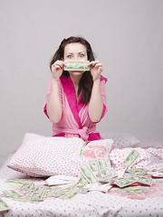 Image showing Girl sitting on the bed rejoices money