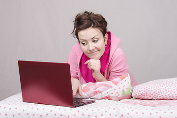 Image showing girl on bed looking with interest at laptop