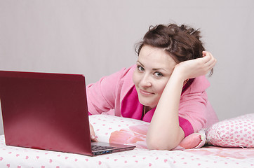 Image showing Happy girl in bed works for laptop