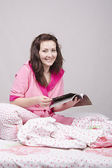 Image showing The girl in bed reading a magazine