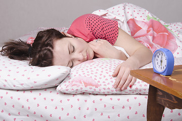 Image showing Girl wakes ringing alarm clock