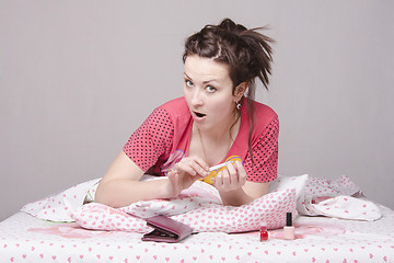 Image showing Girl takes care of the nails lying in bed