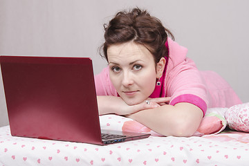 Image showing Thoughtful girl in bed works for laptop