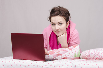 Image showing The girl lying in bed works for laptop