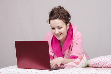 Image showing Happy girl in bed works for laptop