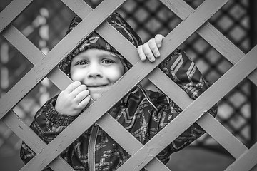 Image showing little baby boy  looking through blue fence