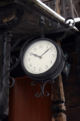 Image showing ancient clock hanging near the wooden building