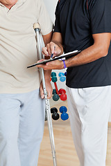 Image showing Trainer Holding Clipboard While Standing With Senior Man On Crut