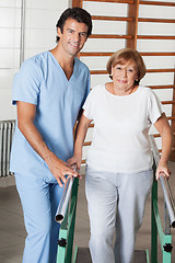 Image showing Therapist Assisting Senior Woman To Walk With The Support Of Bar