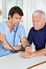 Image showing Male Nurse Checking Blood Pressure Of a Senior Man